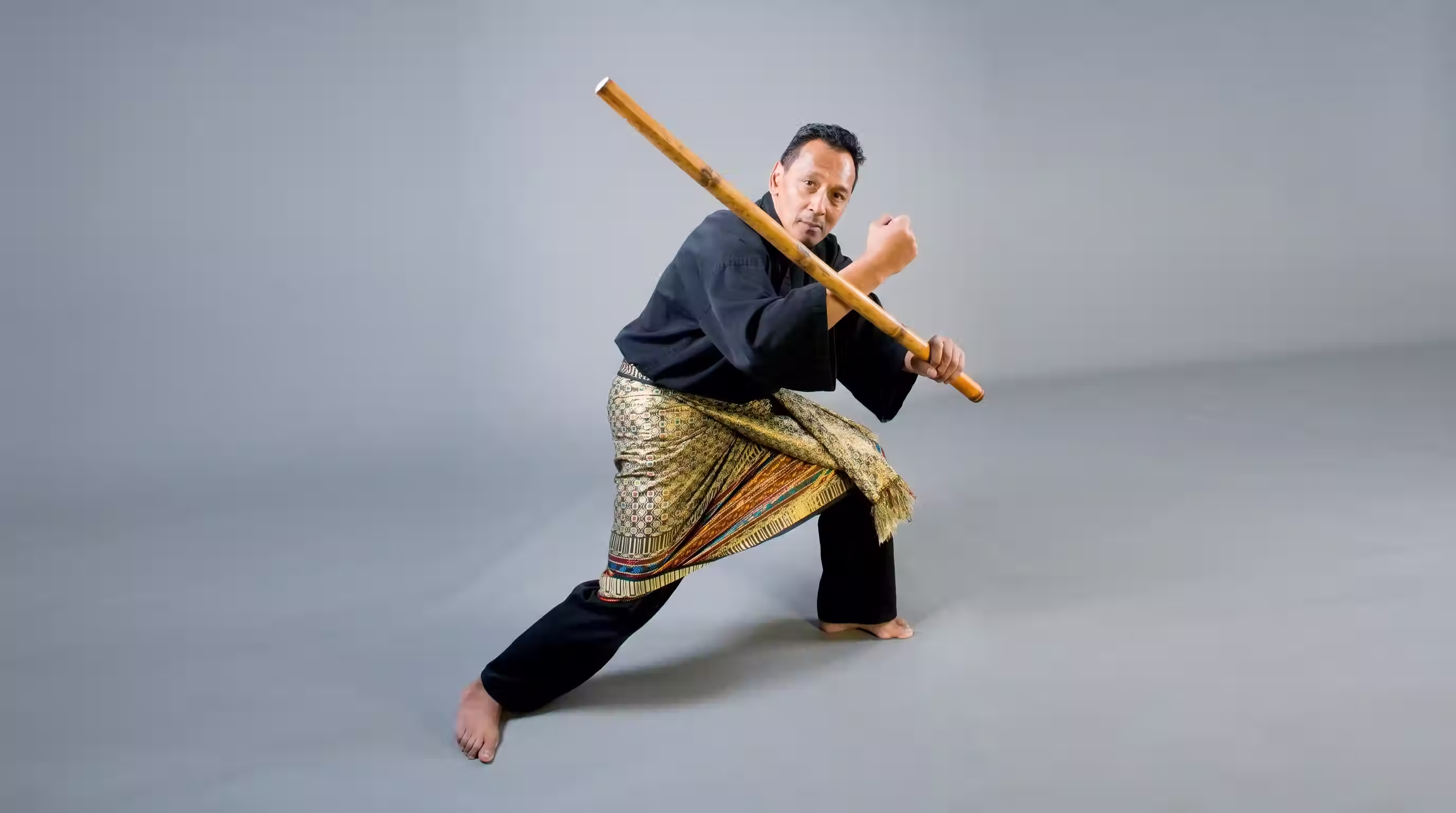 Een pesilat in gevechtshouding met het pencak silat wapen de toya